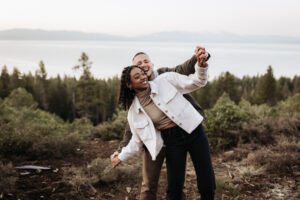 Engaged couple watches the sunrise over Lake Tahoe from a scenic mountaintop