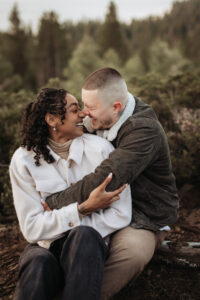 Windblown couple shares a joyful moment during a sunrise engagement in Lake Tahoe