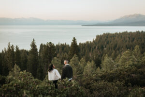 Couple holds hands and soaks in the sunrise during their engagement session in Lake Tahoe