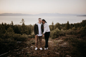 Candid engagement moment as the couple laughs together on a mountaintop at sunrise