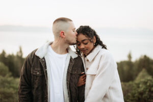 Candid engagement moment as the couple shares intimate moment together on a mountaintop at sunrise