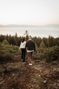 ngaged couple holds hands, soaking in the sunrise at a scenic overlook in Lake Tahoe